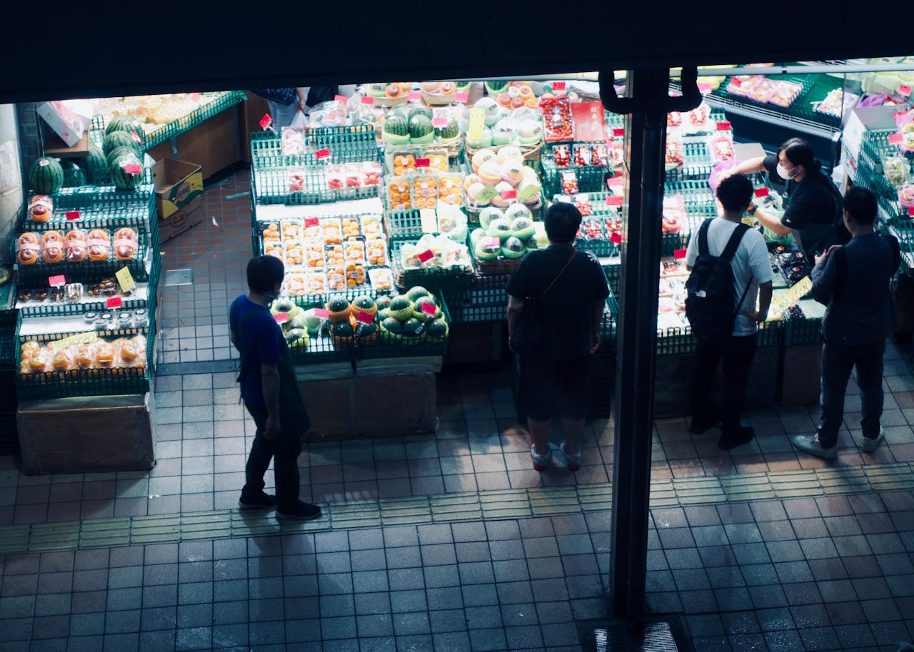 services-01 Vibrant night market scene showcasing a variety of fresh fruits and customers browsing.
